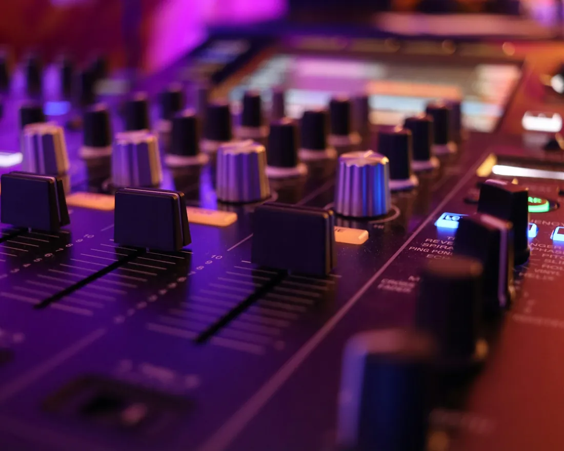 Mesa de mezclas de un estudio de grabación con faders, potenciómetros y vúmetros iluminados
